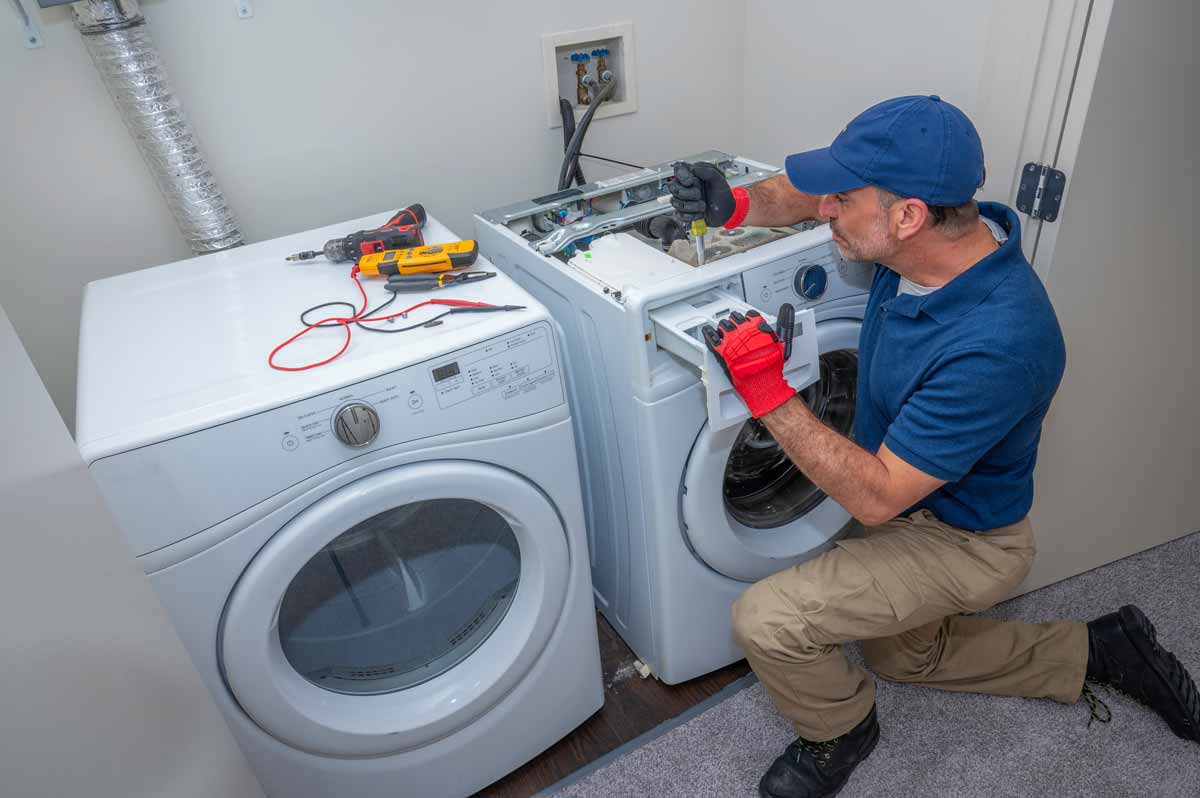 A technician repairing the detergent drawer on a washing machine